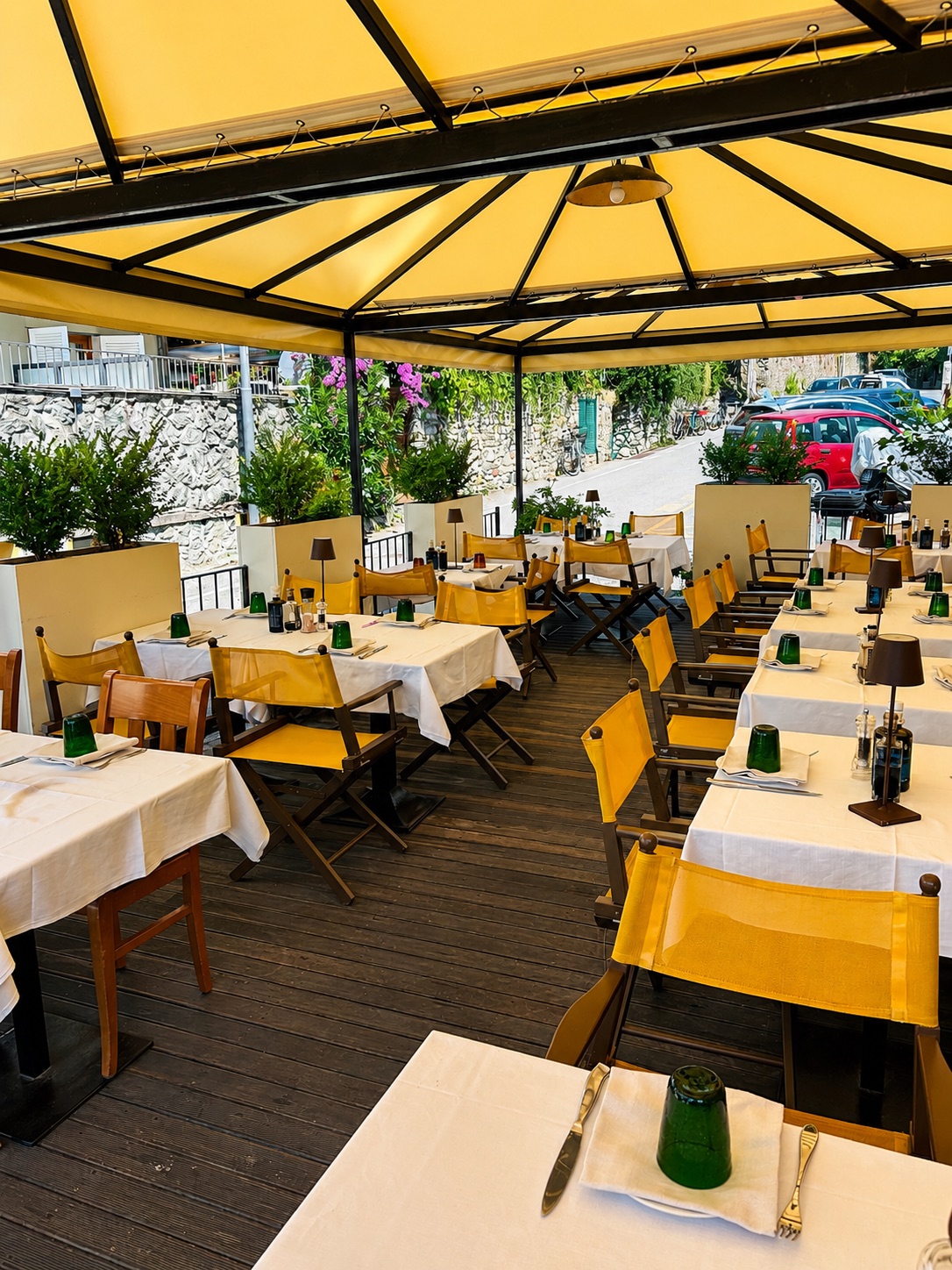 Dehors coperto de La Taverna con tavoli apparecchiati e sedute gialle
