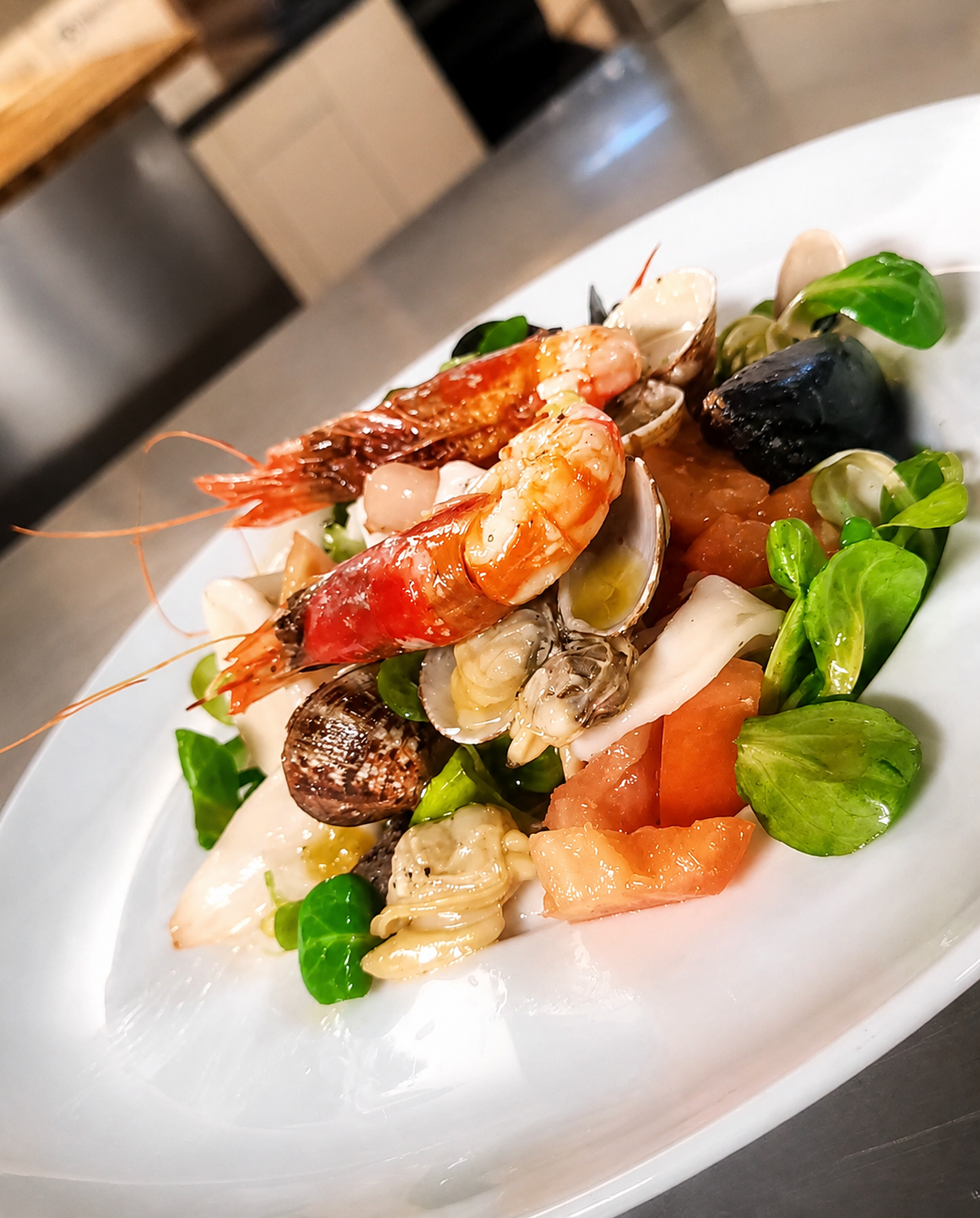 Insalata di mare con gamberi, vongole, cozze, calamari, pomodori e valeriana
