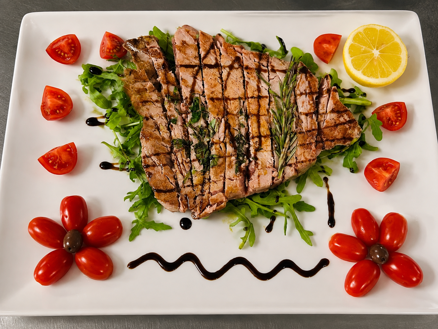 Tagliata di tonno con rucola, pomodorini, limone, rosmarino e crema balsamica